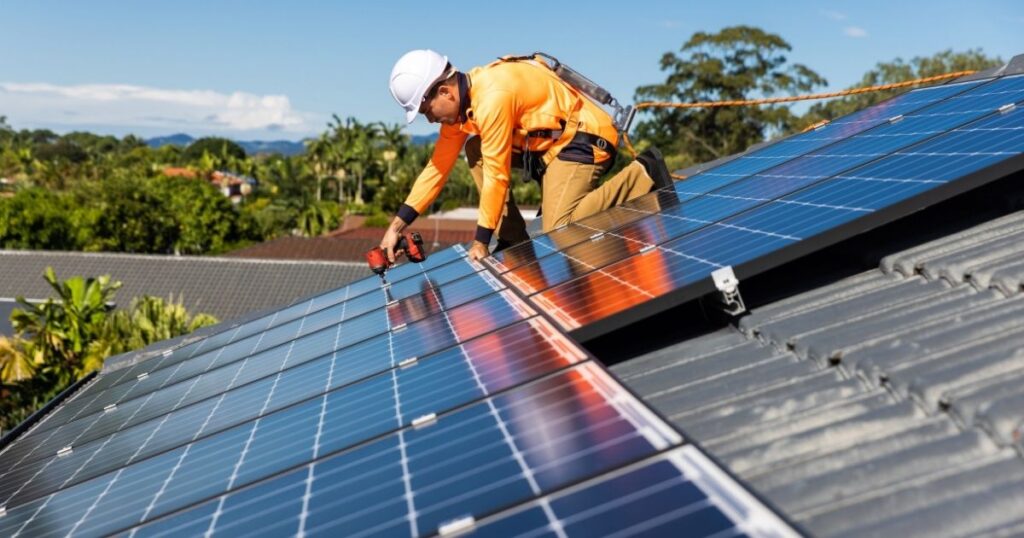 Worker installing solar panels on residential roof