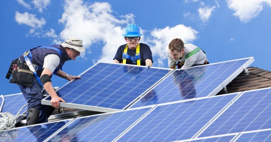 Workers installing solar panels on a roof.