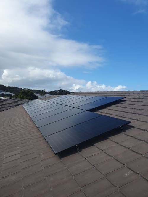 Solar panels installed on a rooftop under blue sky.