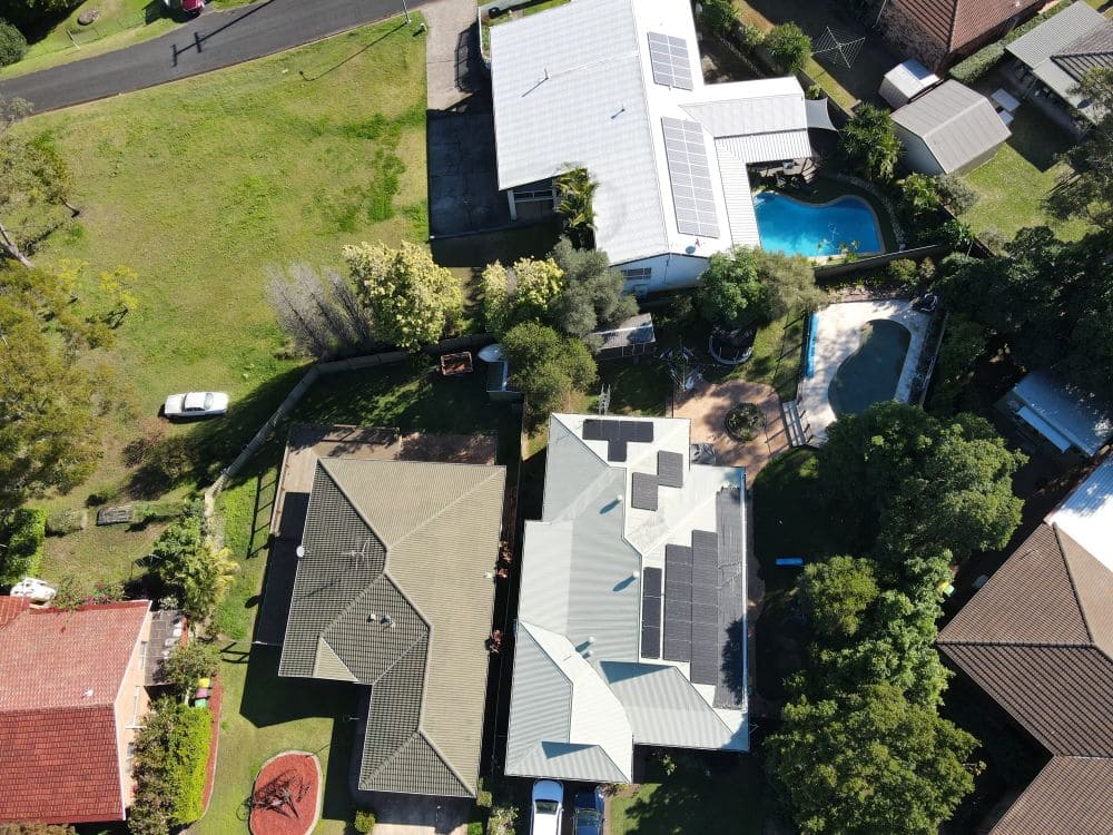 Aerial view of homes with solar panels and pool.