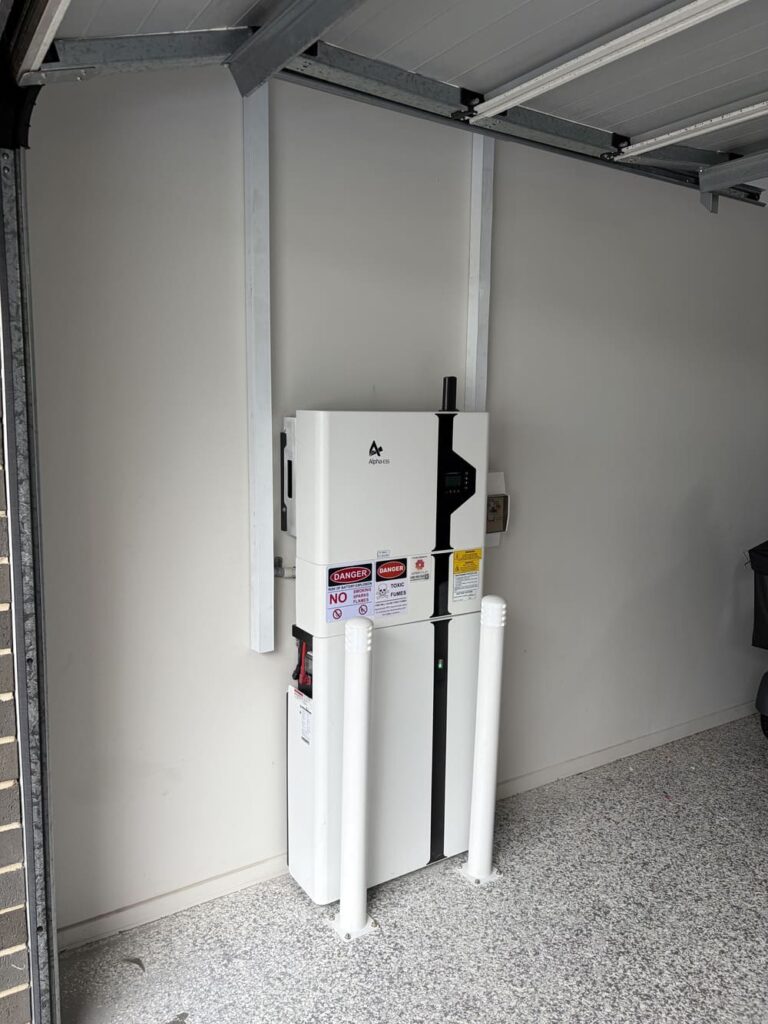 Wall-mounted home battery system in garage with bollards